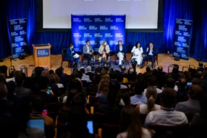 Six people on stage in front of large crowd